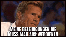 a man with a microphone in his ear says meine beledigungen die muss man sich verdienen .