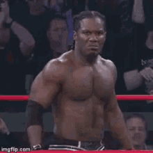 a shirtless man with braids is smiling in a dark room .