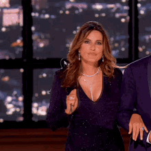 a woman in a purple dress stands next to a man in a blue suit
