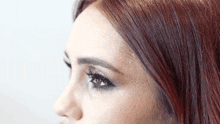 a close up of a woman 's face with red hair and makeup