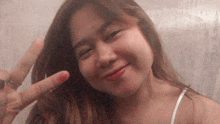 a young woman is giving a peace sign with her hand .