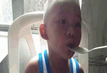 a young boy is holding a spoon in his mouth while sitting in a chair