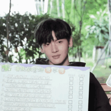 a young man is holding a sign with chinese writing