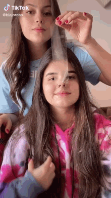 two girls are holding a condom in their hair and one of them is wearing a nose ring .