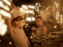 a woman in a bandana stands in front of a building that is on fire