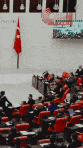 a group of people sitting in red chairs in front of a sign that says tbmm canli