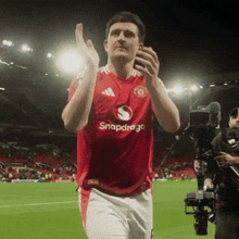 a man wearing a red snapdragon jersey applauds