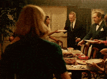 a group of people are gathered around a table with plates of food on it