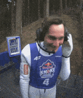 a man wearing headphones and a blue shirt that says " red bull " on it