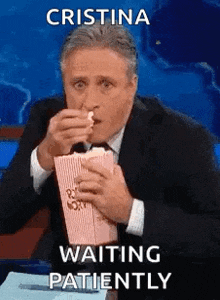a man in a suit and tie is eating popcorn while sitting on a stage .