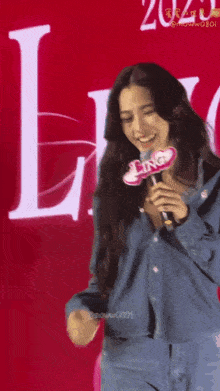 a woman in a denim shirt is holding a microphone with the word ling on it