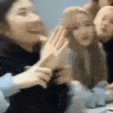 a group of young women are sitting around a table laughing and playing with each other .
