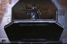 a man in a helmet is standing in a dark room with the door open