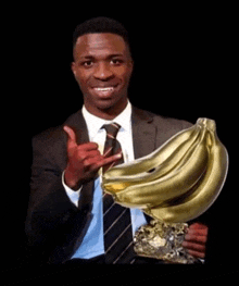 a man in a suit and tie is holding a trophy with bananas on it