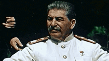 a man with a mustache wearing a white uniform has a medal on his chest