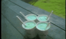 four cups of ice cream with spoons on a table