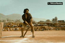 a man with a beard is holding a bat in front of a crowd and a sign that says " x7wickreddy "