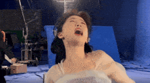 a woman with her mouth open is laying in a chair