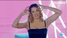 a woman in a black dress is making a funny face while holding her hair .