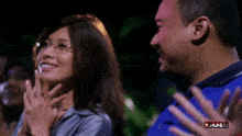 a man and a woman are clapping in front of a screen that says " full "