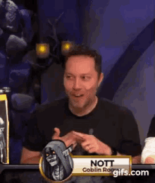 a man is sitting at a table with a sign that says ' nott ' on it .