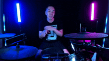 a man wearing a black shirt with the letter t on it is playing drums