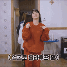 a woman in a red sweatshirt is standing in a hallway with chinese writing on the bottom