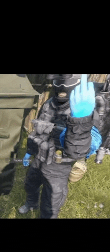 a soldier wearing a mask and gloves is giving a middle finger .