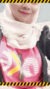 a woman wearing a hijab and a pink shirt that says 20