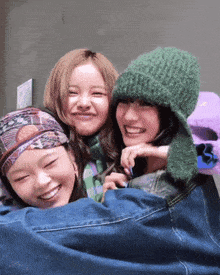 three girls are posing for a picture and one of them has a green hat on