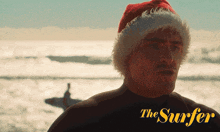 a man wearing a santa hat with the words the surfer on the bottom