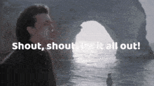 a man stands in front of a cave with the words " shout shout let it all out " above him