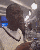 a man in a white sweater holds a glass of white wine