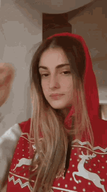 a woman wearing a red christmas sweater with a deer on it .