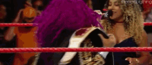 a woman in a purple outfit is standing in a wrestling ring with a microphone .