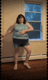 a woman dancing in front of a window in a room