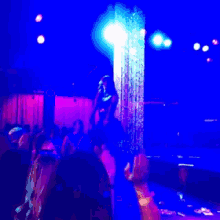 a woman is dancing on a stage in front of a blue curtain