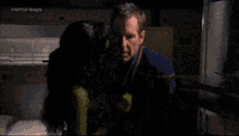a man and a woman are hugging in a dark room with a sign that says mental illness in the background