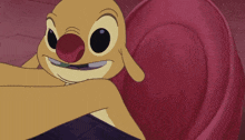 a cartoon character with a red nose is laying on a red pillow