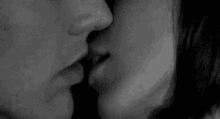 a black and white photo of a man and woman kissing each other .