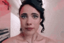 a woman without a shirt is taking a selfie in a bathroom .