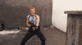 a man is holding a gun while standing in a alleyway .