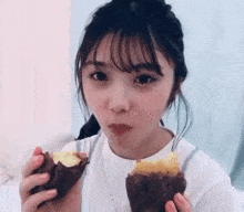 a young woman is eating two sweet potatoes in her hand .