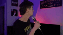 a man is holding a microphone in front of a sign that says wednesdays