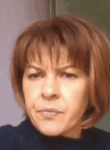 a close up of a woman 's face with short red hair and a black shirt .