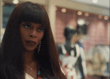 a woman wearing a necklace with a cross on it stands in front of a mannequin
