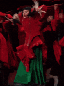 a woman in a red dress and green skirt is dancing with other women