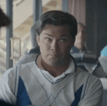a man is making a funny face while sitting at a table .