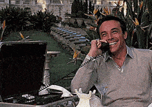 a man is sitting in front of a briefcase and talking on a phone