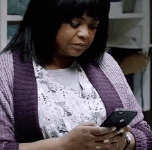 a woman in a purple sweater is looking at her phone .